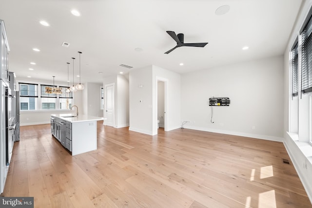 kitchen featuring light wood-style flooring, recessed lighting, a sink, light countertops, and ceiling fan with notable chandelier