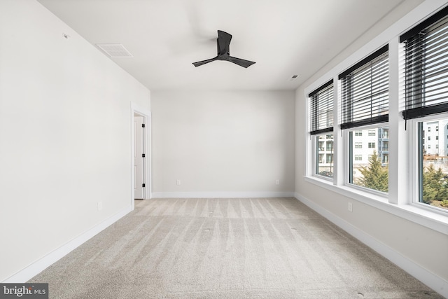 empty room with visible vents, baseboards, light colored carpet, and a ceiling fan