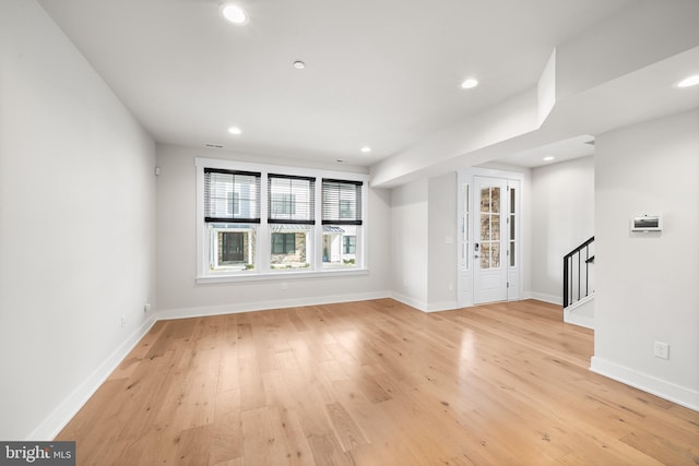 unfurnished living room with stairway, recessed lighting, baseboards, and light wood finished floors