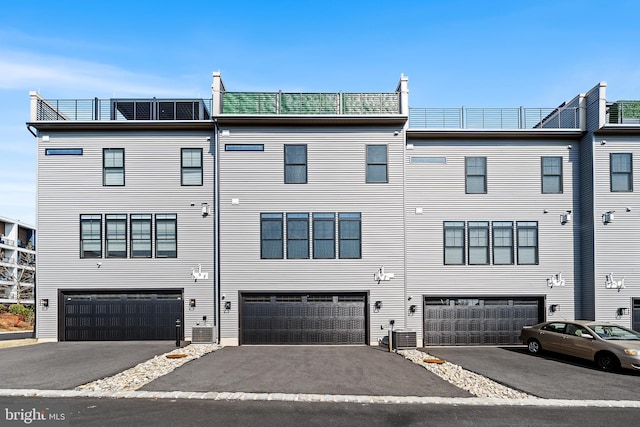 view of front of home featuring central AC unit, a garage, and driveway