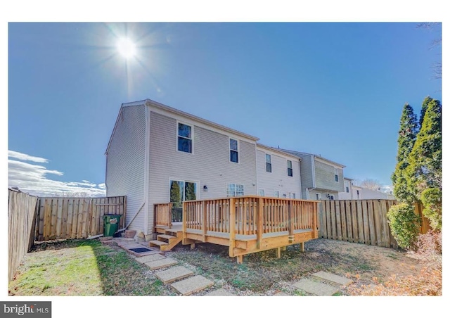 rear view of house featuring a wooden deck and a fenced backyard