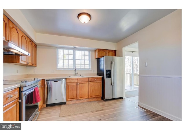 kitchen with a sink, stainless steel appliances, under cabinet range hood, and light countertops