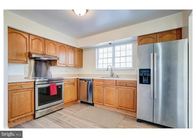 kitchen with under cabinet range hood, appliances with stainless steel finishes, light countertops, and a sink