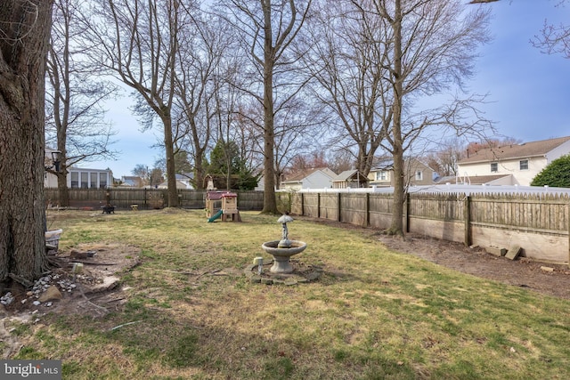 view of yard featuring a playground, a fenced backyard, and a residential view