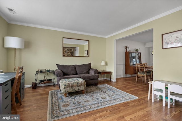 living area with visible vents, crown molding, and wood finished floors