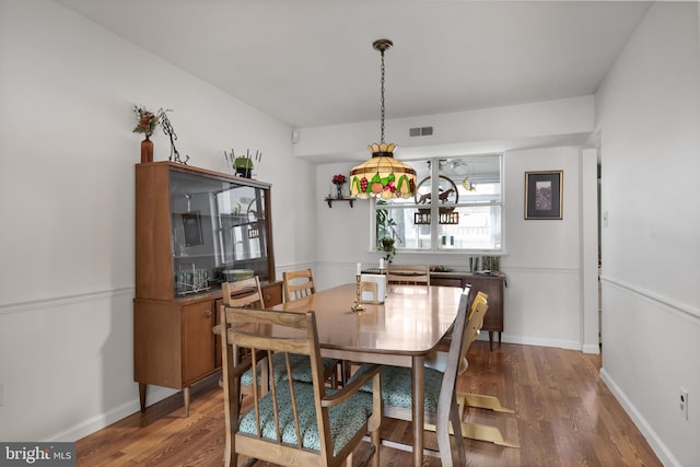 dining room featuring visible vents, baseboards, and wood finished floors