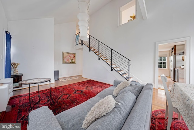 living area with stairway, a high ceiling, baseboards, and wood finished floors