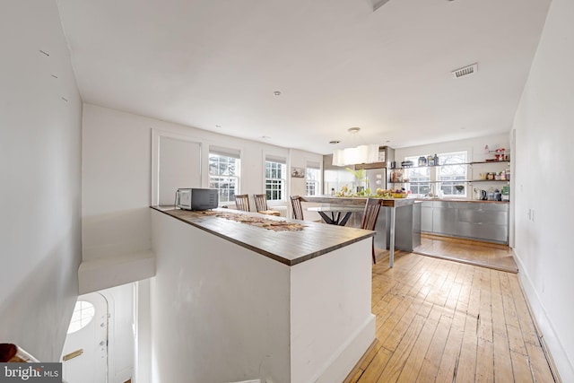 kitchen featuring visible vents, a healthy amount of sunlight, light wood-type flooring, and butcher block counters