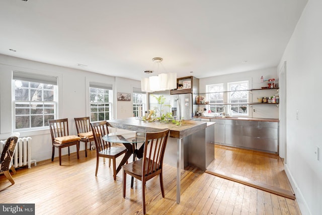 kitchen featuring baseboards, light wood-type flooring, radiator heating unit, stainless steel refrigerator with ice dispenser, and open shelves