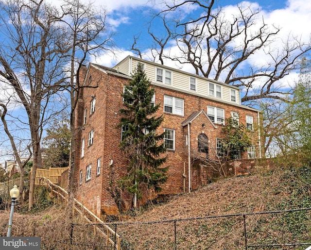 view of front of home featuring brick siding and fence