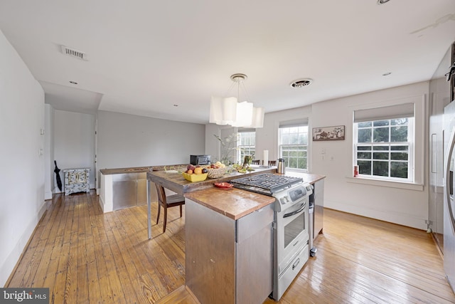 kitchen with butcher block countertops, visible vents, stainless steel gas range, and light wood-type flooring