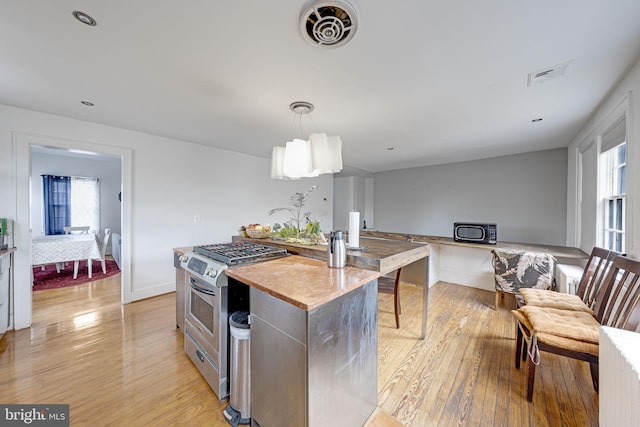 kitchen with visible vents, stainless steel gas stove, light wood finished floors, and a center island