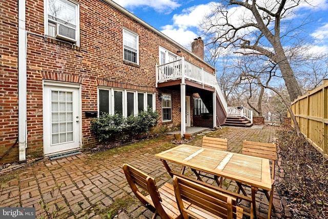 back of property with fence, outdoor dining area, a chimney, a patio area, and brick siding