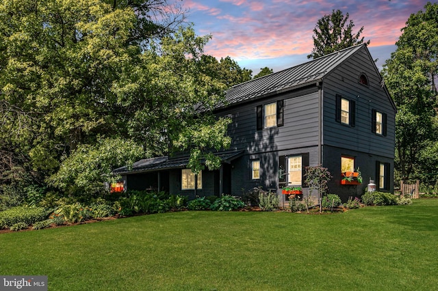 view of front of house with a standing seam roof, a front lawn, brick siding, and metal roof