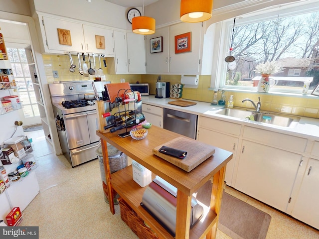 kitchen featuring tasteful backsplash, light countertops, stainless steel appliances, white cabinetry, and a sink