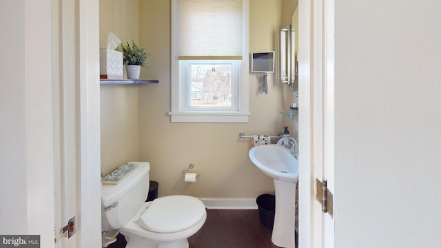 half bath with a sink, baseboards, and toilet