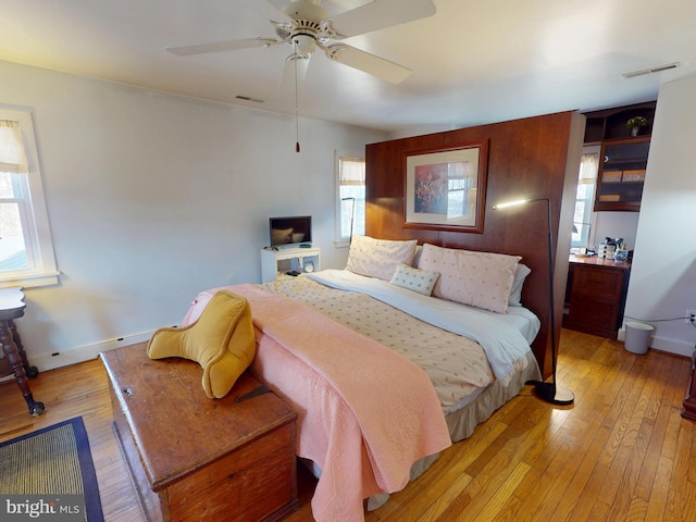 bedroom featuring light wood-style floors, visible vents, and baseboards