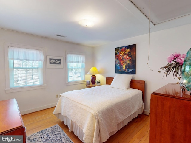 bedroom with visible vents, baseboards, attic access, and light wood-style flooring