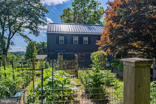 exterior space featuring a standing seam roof, metal roof, a vegetable garden, and fence