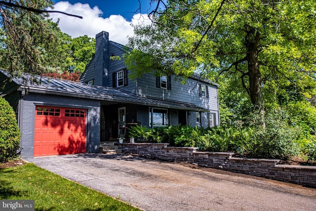 view of front of house featuring a standing seam roof, aphalt driveway, metal roof, a garage, and brick siding