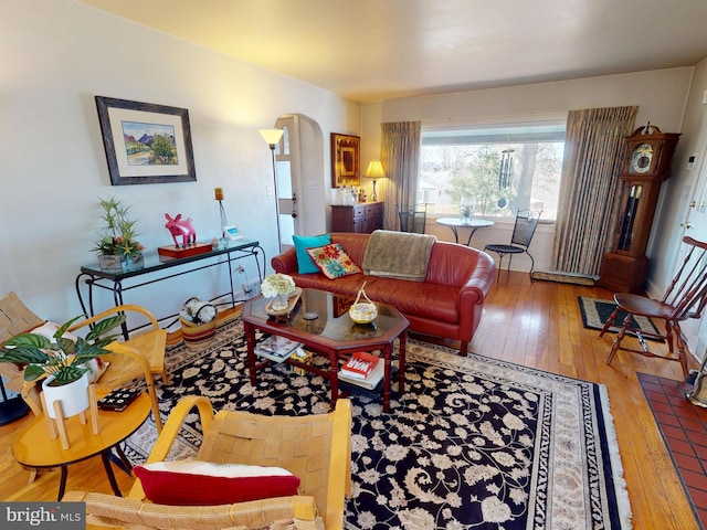 living area with arched walkways and hardwood / wood-style floors