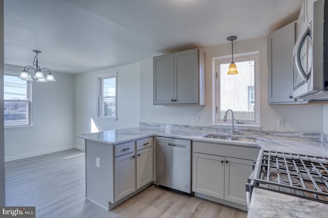 kitchen with a healthy amount of sunlight, appliances with stainless steel finishes, a peninsula, and a sink