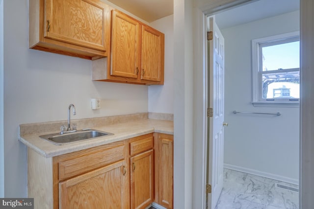 kitchen featuring baseboards, visible vents, a sink, light countertops, and marble finish floor