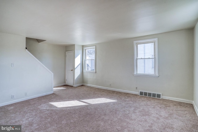 carpeted spare room featuring visible vents and baseboards