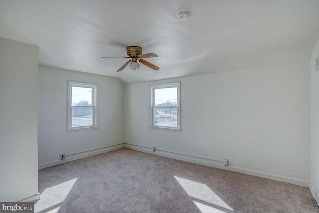 empty room featuring a ceiling fan, light colored carpet, and baseboards