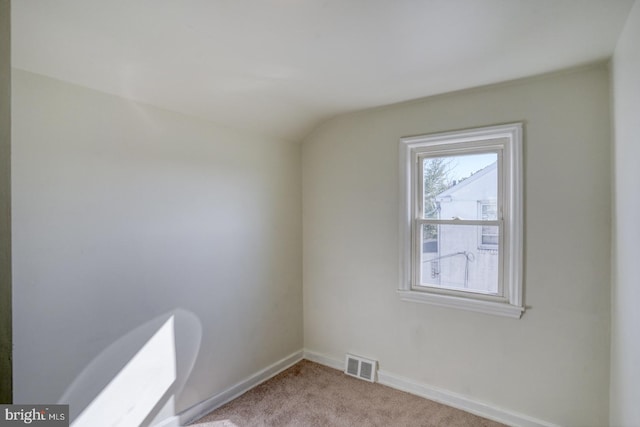 carpeted empty room featuring visible vents, baseboards, and vaulted ceiling