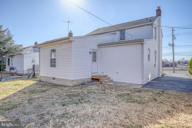 rear view of property with entry steps, crawl space, fence, and a chimney