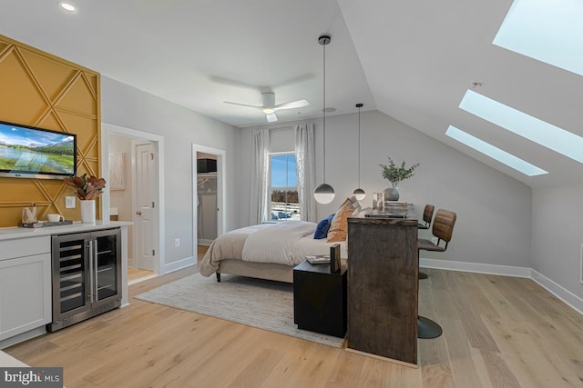 bedroom featuring light wood-type flooring, lofted ceiling with skylight, baseboards, and beverage cooler