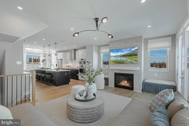 living room with recessed lighting, light wood-style floors, and a tiled fireplace