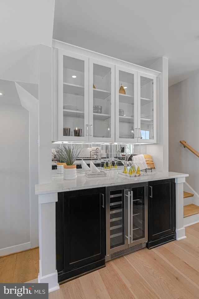 bar with wine cooler, stairway, baseboards, and light wood-style floors