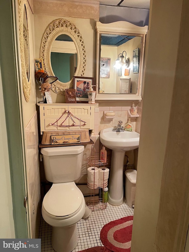 bathroom featuring tile patterned floors, toilet, and tile walls