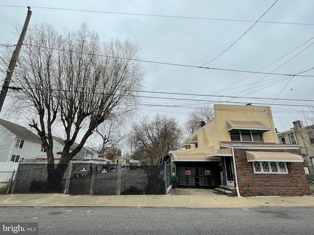 view of front of house with fence private yard, brick siding, and stucco siding