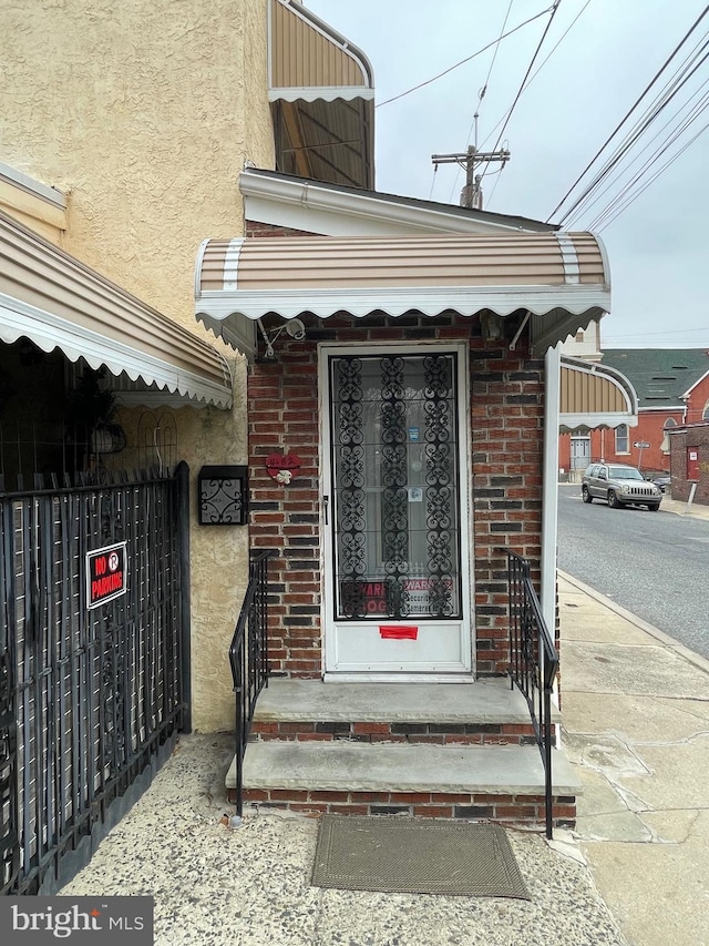 property entrance with brick siding and stucco siding