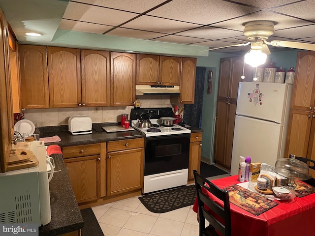 kitchen with brown cabinets, range with electric cooktop, under cabinet range hood, backsplash, and freestanding refrigerator