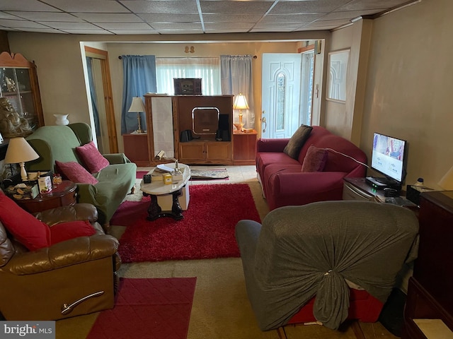 living area with a paneled ceiling and carpet