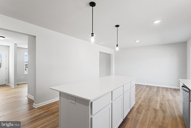 kitchen with a kitchen island, white cabinetry, light wood-style floors, light countertops, and hanging light fixtures