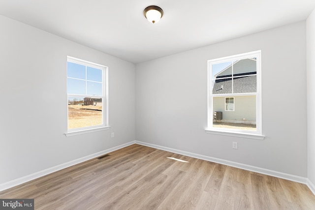 unfurnished room featuring visible vents, baseboards, and wood finished floors