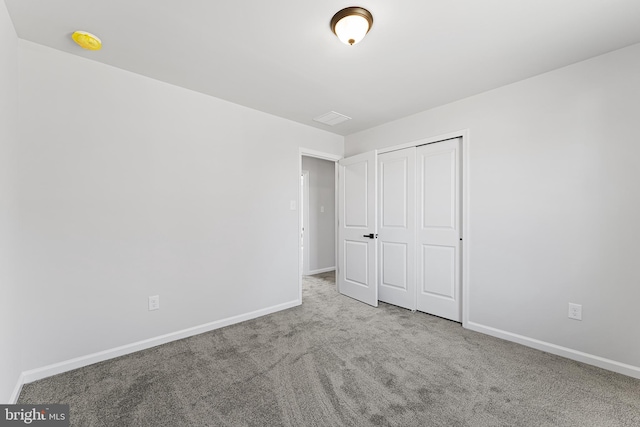 unfurnished bedroom with baseboards, carpet floors, and a closet