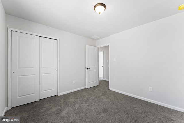 unfurnished bedroom featuring a closet, baseboards, and dark carpet