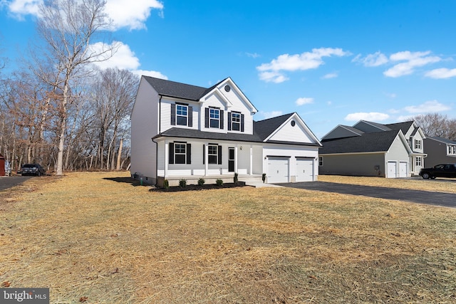 traditional-style home featuring aphalt driveway, a front yard, and a garage