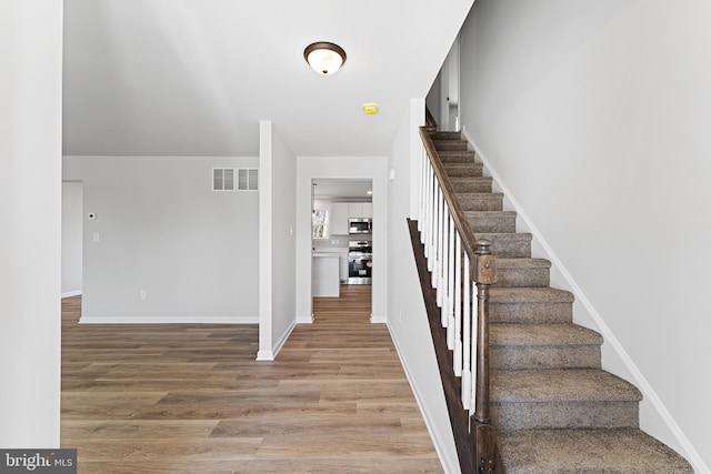 stairs featuring visible vents, baseboards, and wood finished floors