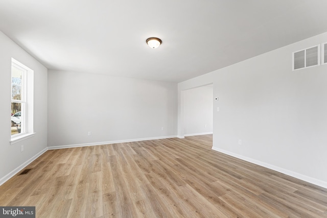 unfurnished room with visible vents, light wood-type flooring, and baseboards