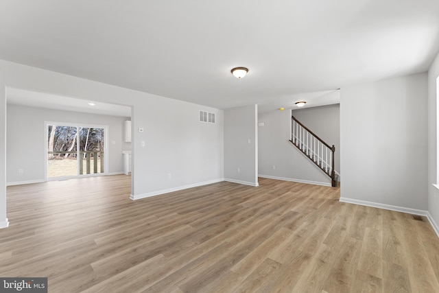 spare room featuring visible vents, stairway, light wood-style floors, and baseboards