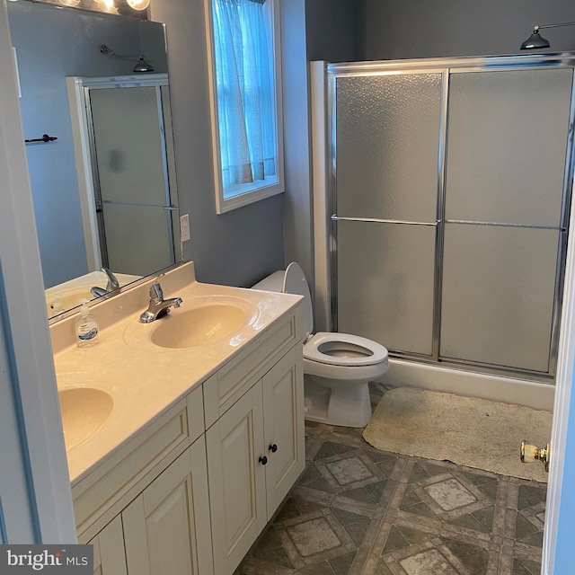 full bathroom featuring a shower stall, toilet, double vanity, and a sink