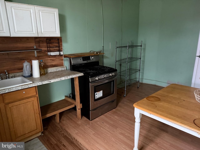 kitchen featuring a sink, light countertops, stainless steel gas range, and light wood finished floors