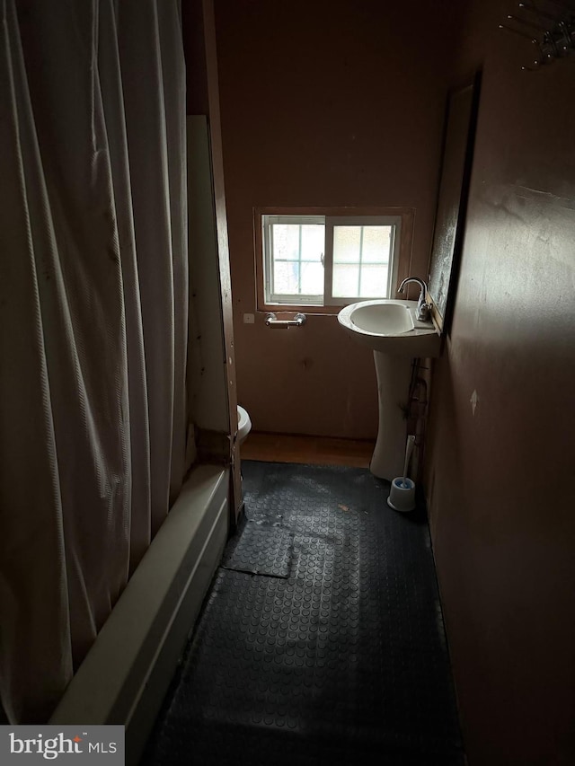 full bathroom featuring a sink, shower / bath combo with shower curtain, and toilet